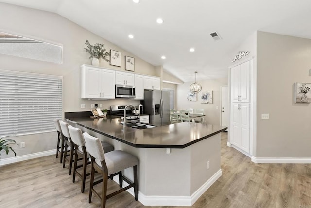 kitchen with a sink, vaulted ceiling, stainless steel appliances, and visible vents