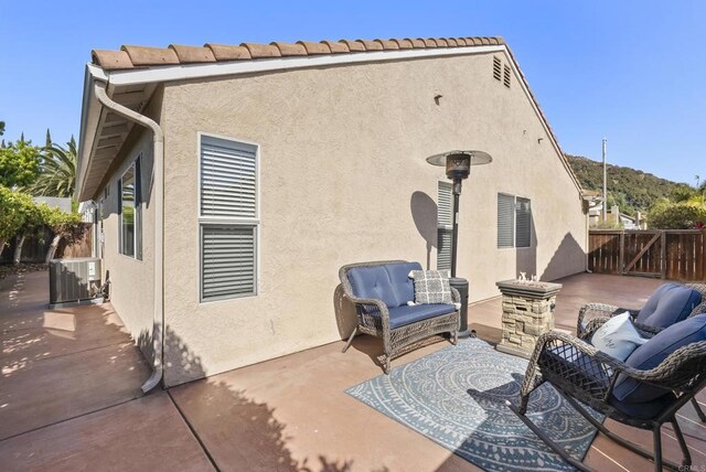 back of property featuring central AC unit, a patio area, stucco siding, and fence