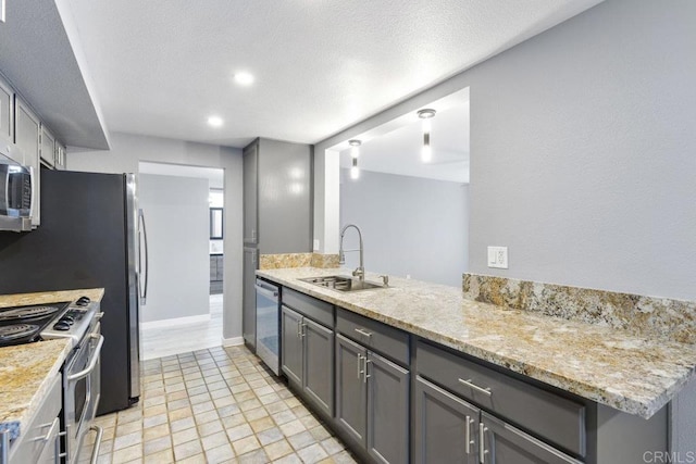 kitchen featuring recessed lighting, light stone counters, a sink, gray cabinetry, and stainless steel appliances