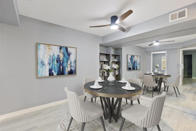 dining area with baseboards, ceiling fan, light wood finished floors, and visible vents