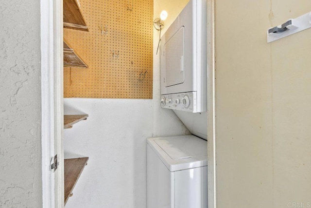 clothes washing area featuring stacked washer and clothes dryer and laundry area