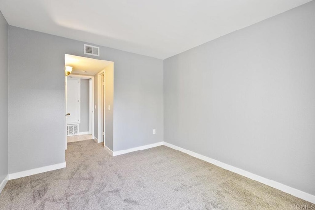 empty room with carpet floors, baseboards, and visible vents
