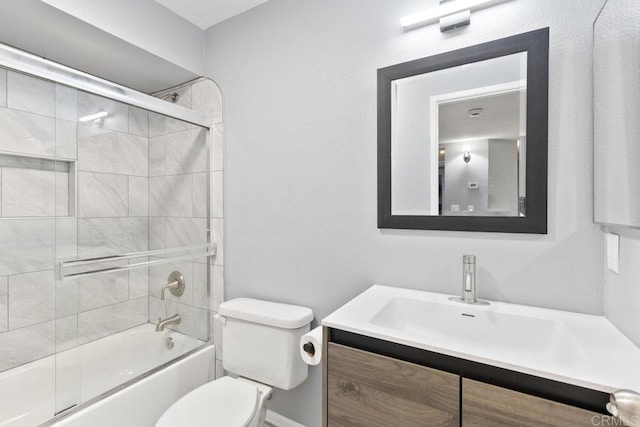 bathroom featuring toilet, shower / bath combination with glass door, and vanity