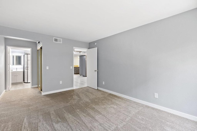 unfurnished bedroom with baseboards, carpet flooring, connected bathroom, and visible vents