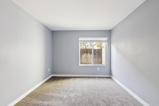 spare room with carpet flooring, baseboards, and a textured wall