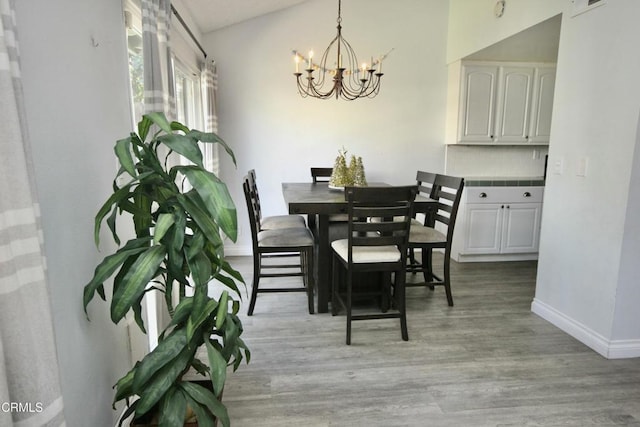 dining room featuring baseboards, an inviting chandelier, and light wood-style flooring