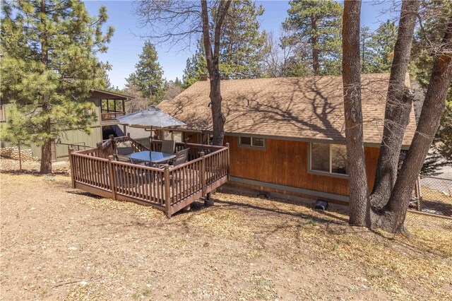 back of property featuring roof with shingles, fence, and a wooden deck