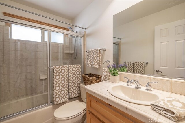 bathroom featuring toilet, combined bath / shower with glass door, and vanity