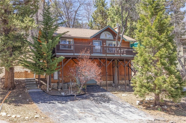rustic home with aphalt driveway, a wooden deck, and cooling unit