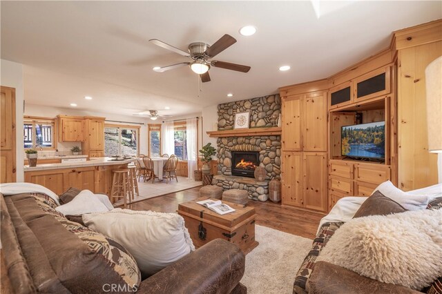living room featuring a ceiling fan, recessed lighting, light wood-type flooring, and a fireplace