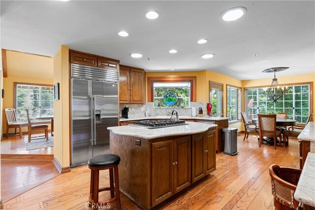 1031 Black Oaks Dr, Lake Arrowhead, CA 92352 - kitchen featuring appliances with stainless steel finishes, light wood finished floors, a kitchen island, backsplash, and decorative light fixtures