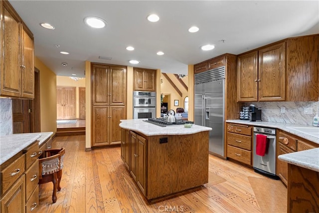 1031 Black Oaks Dr, Lake Arrowhead, CA 92352 - kitchen with stainless steel appliances, light wood-type flooring, a center island, brown cabinets, and decorative backsplash