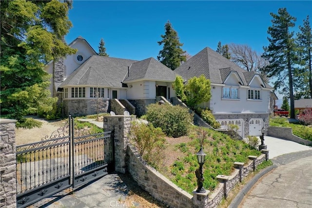 1031 Black Oaks Dr, Lake Arrowhead, CA 92352 - view of front facade featuring stone siding, driveway, an attached garage, stucco siding, and a gate