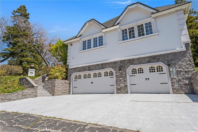 1031 Black Oaks Dr, Lake Arrowhead, CA 92352 - view of front of house with stone siding, an attached garage, concrete driveway, and stucco siding