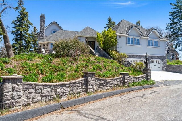 1031 Black Oaks Dr, Lake Arrowhead, CA 92352 - view of front facade featuring a garage, a chimney, stucco siding, concrete driveway, and stone siding