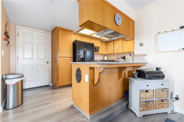 9375 Musselman Dr Unit A, Atascadero, CA 93422 - kitchen with a peninsula, a kitchen breakfast bar, light wood-type flooring, under cabinet range hood, and black fridge