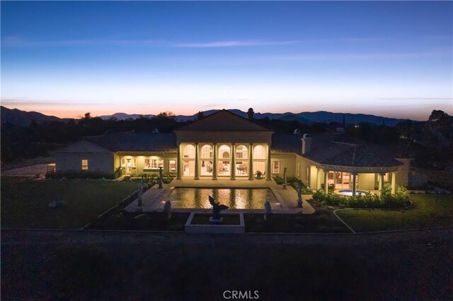 back of property at dusk with a patio area and an outdoor pool