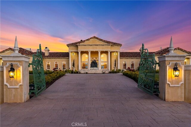 view of front facade featuring decorative driveway, stucco siding, and a gate