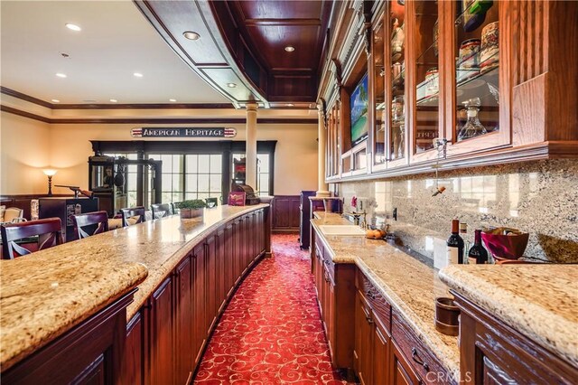 interior space with decorative columns, crown molding, a community bar, a wainscoted wall, and dark carpet
