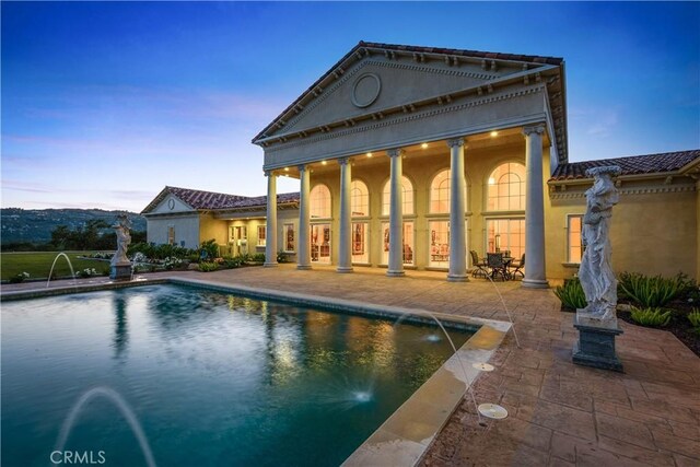 back of property featuring a patio, stucco siding, and an outdoor pool