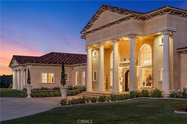 view of front of property with an attached garage, stucco siding, a yard, and driveway
