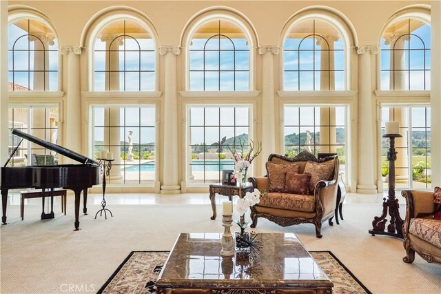 interior space with decorative columns, carpet flooring, and a towering ceiling