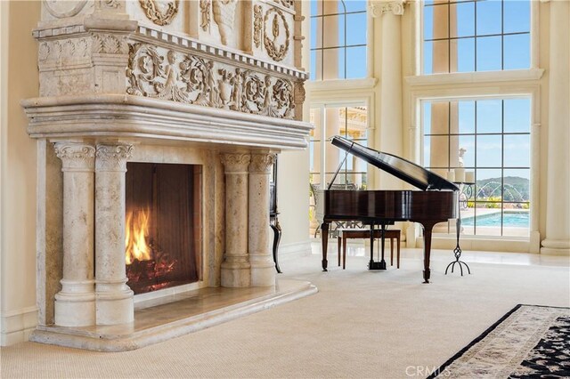 living area featuring carpet, a fireplace, decorative columns, and a towering ceiling