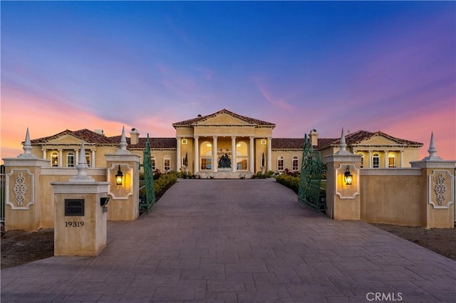 view of front of house with a gate, stucco siding, fence private yard, and decorative driveway