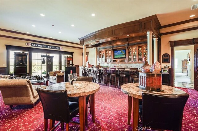 dining space with a community bar, recessed lighting, ornamental molding, and dark carpet