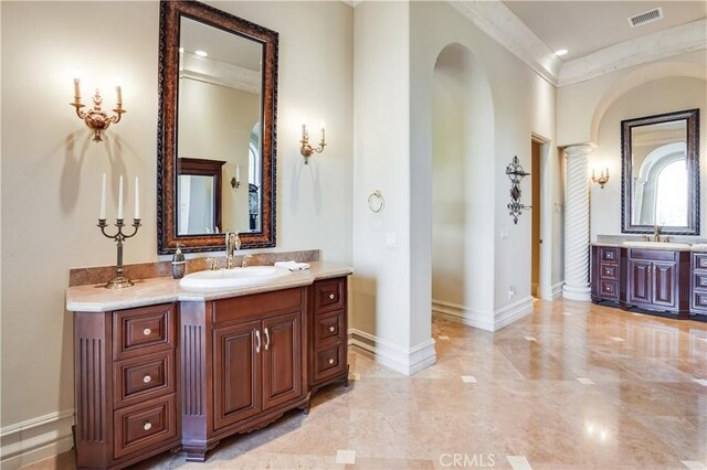 bathroom featuring visible vents, ornamental molding, baseboards, two vanities, and a sink