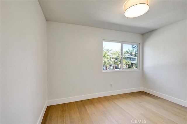 spare room featuring baseboards and light wood-type flooring