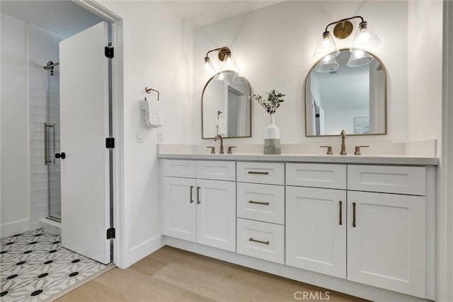 bathroom with double vanity, baseboards, a shower stall, and a sink