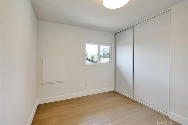 spare room featuring baseboards and light wood finished floors