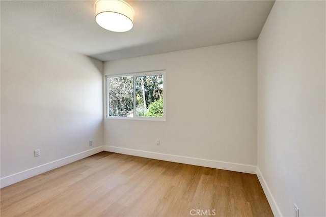 empty room featuring baseboards and light wood-style flooring