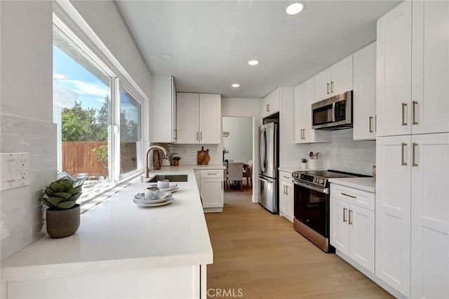 kitchen with a sink, appliances with stainless steel finishes, tasteful backsplash, and light countertops