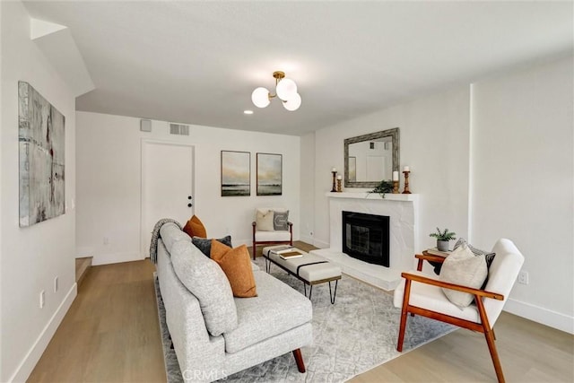 living area featuring baseboards, wood finished floors, visible vents, and a fireplace