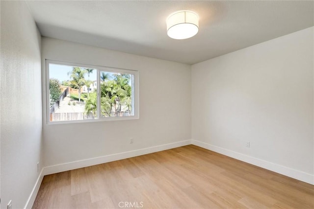 unfurnished room featuring baseboards and light wood finished floors