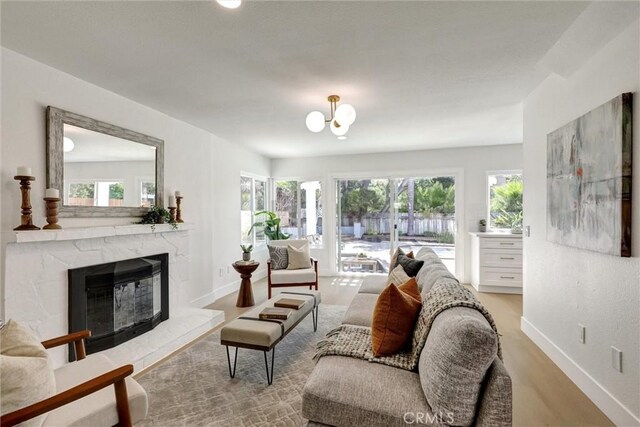living area featuring baseboards, a high end fireplace, wood finished floors, and an inviting chandelier