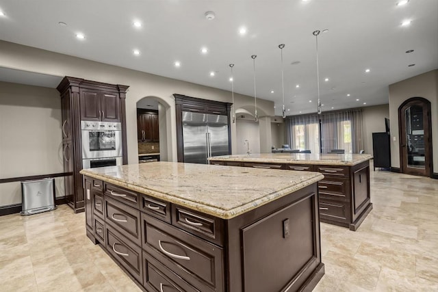 2890 Gate Fifteen Pl, Chula Vista, CA 91914 - kitchen with a large island with sink, stainless steel appliances, arched walkways, dark brown cabinets, and recessed lighting