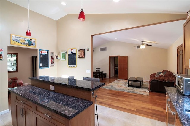 kitchen with visible vents, a breakfast bar, open floor plan, and lofted ceiling