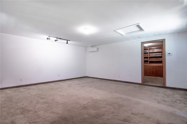 spare room with baseboards, attic access, carpet, and track lighting