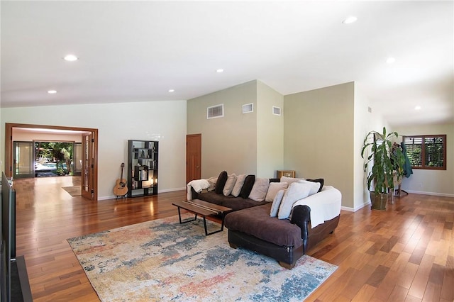 living room featuring baseboards, visible vents, wood finished floors, and lofted ceiling