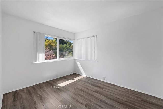 spare room featuring baseboards and wood finished floors