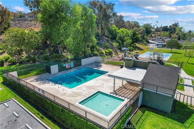 community pool with fence, a patio, and a lawn