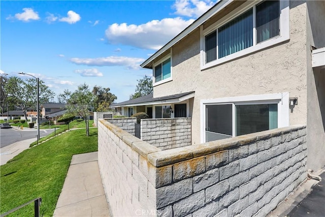 view of side of property with a lawn and stucco siding