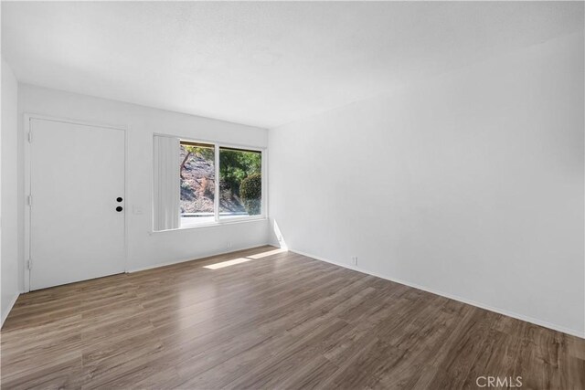 unfurnished room with baseboards and wood finished floors