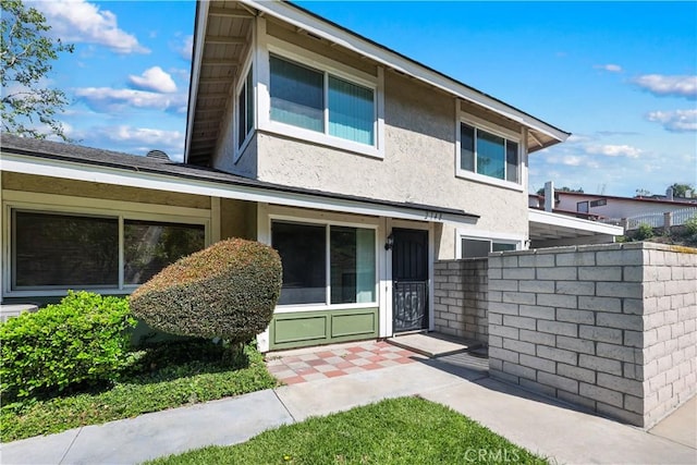 view of front facade featuring stucco siding and fence