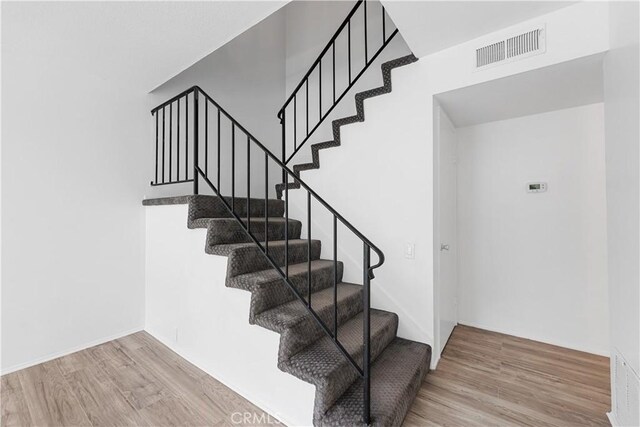 stairs featuring wood finished floors and visible vents