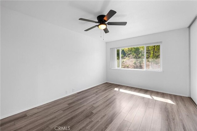 unfurnished room with baseboards, ceiling fan, and wood finished floors