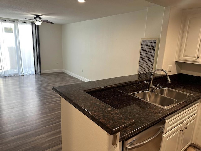 kitchen featuring dark wood-style flooring, dishwasher, a sink, baseboards, and a peninsula